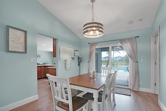 dining space featuring baseboards, light wood-style floors, an inviting chandelier, and vaulted ceiling