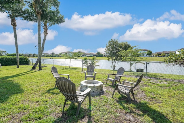 view of yard with fence, a water view, and an outdoor fire pit