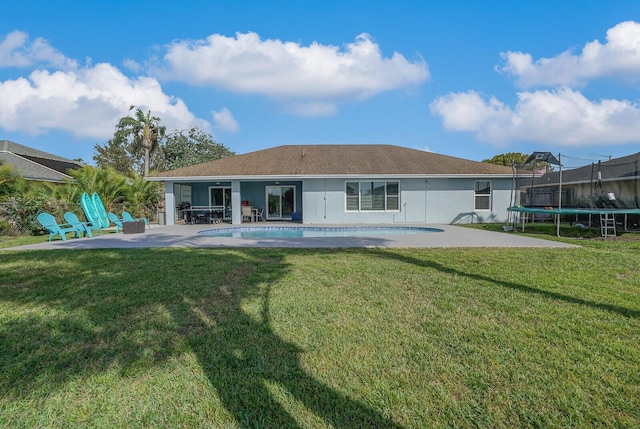 rear view of house with an outdoor pool, a trampoline, a patio area, and a lawn