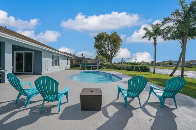 view of pool featuring a lawn, a patio, a playground, and a trampoline