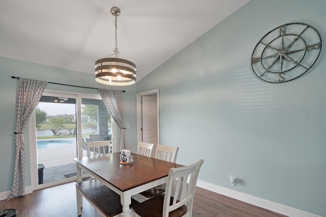 dining area featuring lofted ceiling, a notable chandelier, wood finished floors, and baseboards