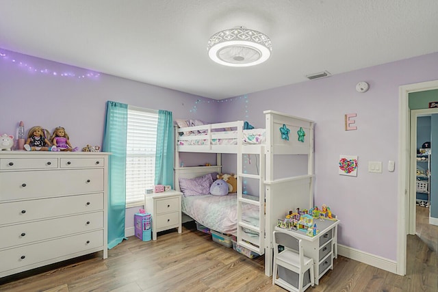 bedroom with wood finished floors, visible vents, and baseboards