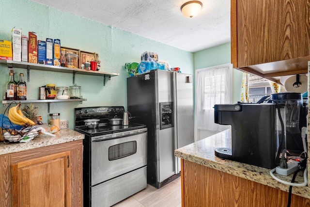 kitchen featuring stainless steel appliances, brown cabinets, a textured ceiling, and light stone countertops