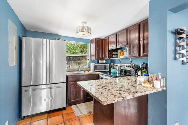 kitchen featuring light tile patterned floors, light stone counters, stainless steel appliances, a peninsula, and a sink