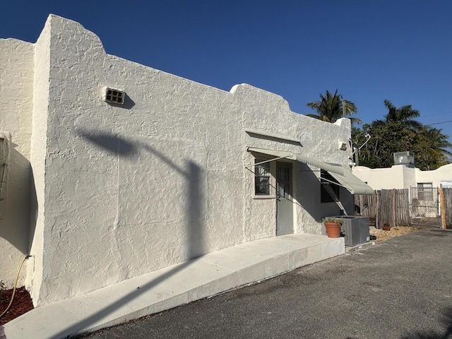 view of home's exterior with cooling unit, fence, and stucco siding