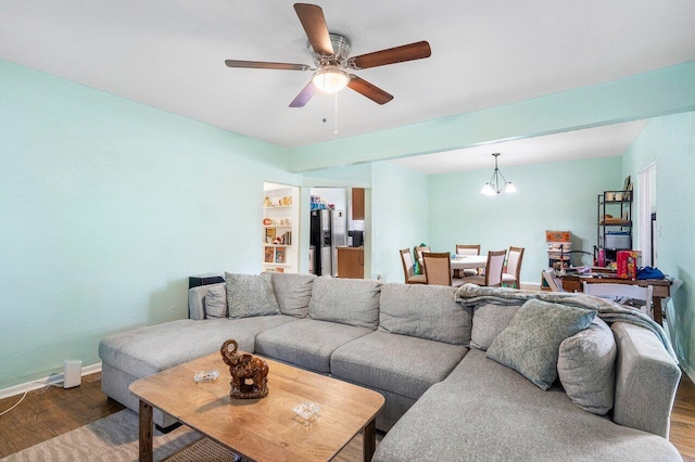 living area featuring ceiling fan with notable chandelier, wood finished floors, built in features, and baseboards