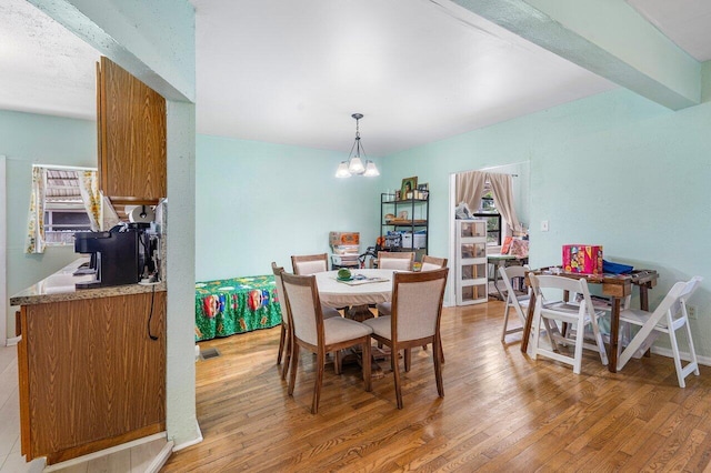 dining area featuring beam ceiling, visible vents, a notable chandelier, and light wood-style flooring