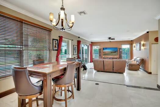 dining area with baseboards, visible vents, crown molding, and ceiling fan with notable chandelier