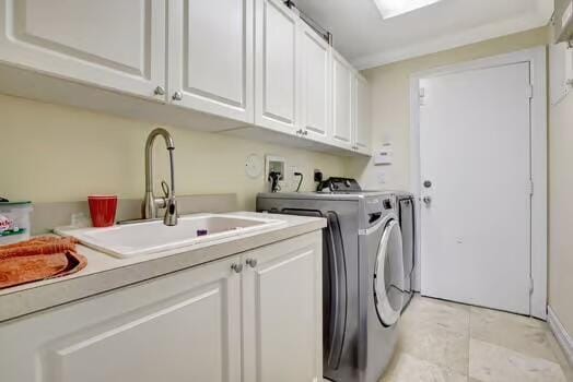 washroom with cabinet space, washing machine and dryer, and a sink