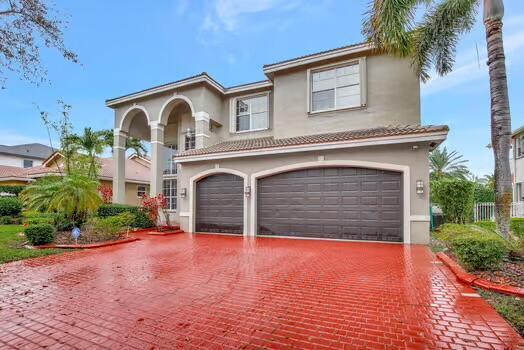 mediterranean / spanish home featuring a garage, decorative driveway, a tile roof, and stucco siding