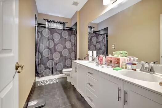 full bathroom featuring double vanity, tile patterned flooring, a sink, and toilet