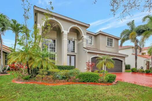 mediterranean / spanish home featuring a front lawn, decorative driveway, an attached garage, and stucco siding