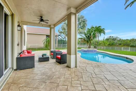 view of swimming pool with a ceiling fan, a pool with connected hot tub, a patio, and fence