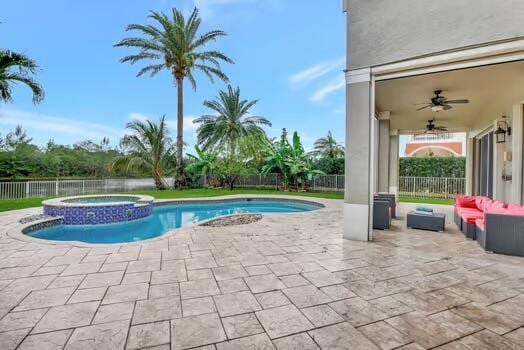 view of swimming pool featuring a ceiling fan, a pool with connected hot tub, a patio area, and a fenced backyard