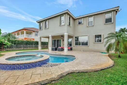 back of house with a pool with connected hot tub, fence, a patio, and stucco siding