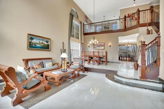 living area with stairs, a towering ceiling, and a notable chandelier