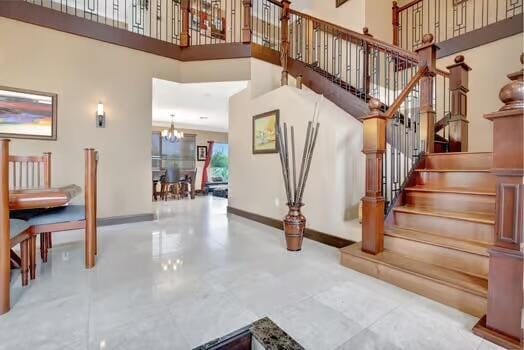 staircase featuring a towering ceiling, baseboards, and an inviting chandelier