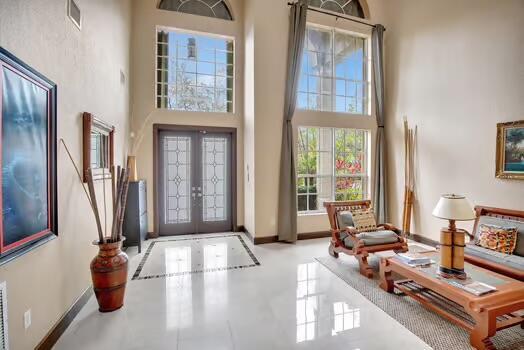 entryway with french doors, baseboards, visible vents, and a high ceiling