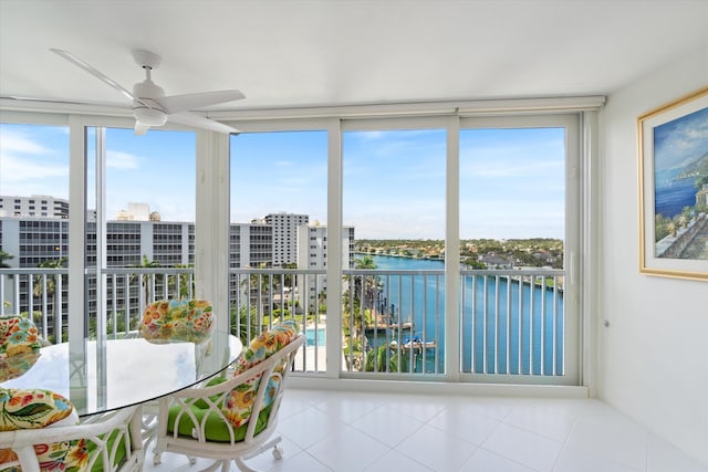 unfurnished sunroom with a water view, ceiling fan, and a city view