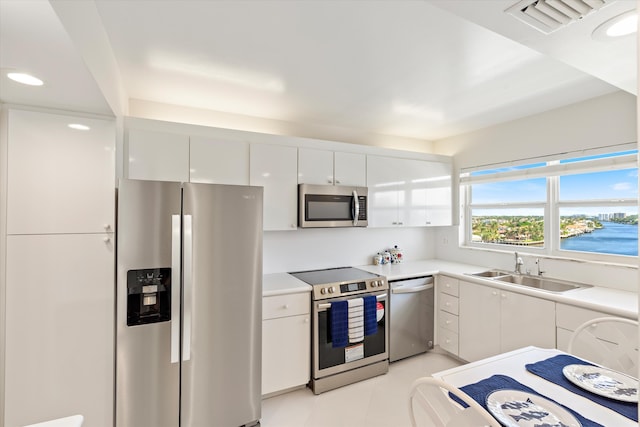 kitchen featuring stainless steel appliances, light countertops, visible vents, white cabinets, and a sink