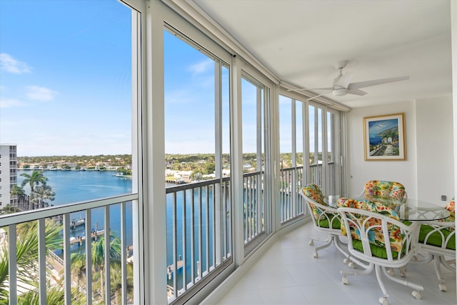 sunroom / solarium featuring a water view and a ceiling fan