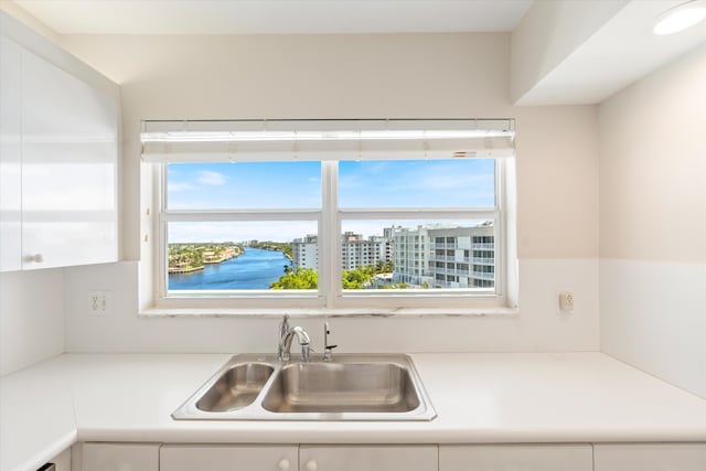 kitchen with light countertops, white cabinets, and a sink