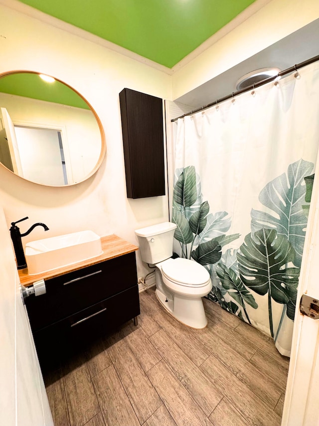 bathroom with toilet, curtained shower, wood finished floors, and vanity