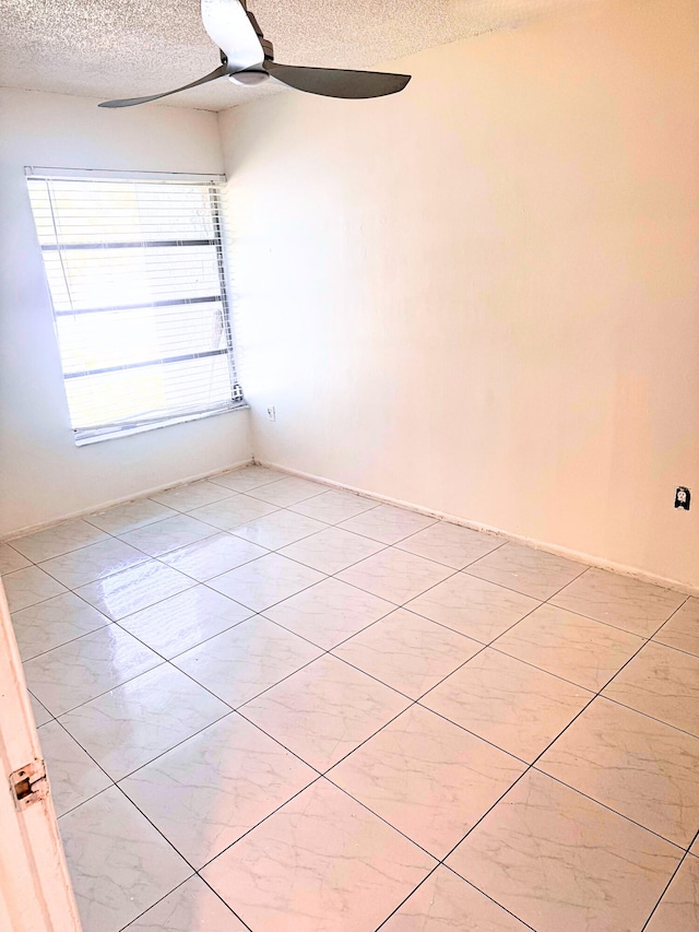 unfurnished room featuring a textured ceiling, light tile patterned floors, and a ceiling fan