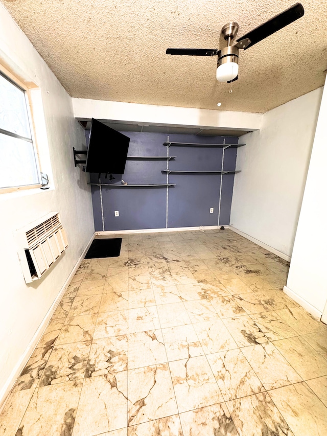 interior space featuring a ceiling fan, a wall unit AC, and baseboards