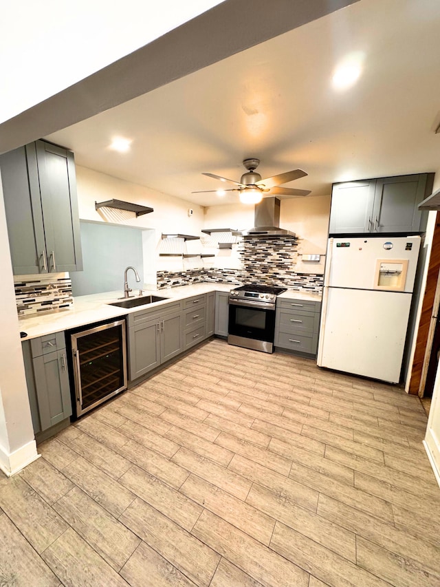 kitchen featuring gray cabinetry, stainless steel range oven, a sink, white fridge with ice dispenser, and beverage cooler