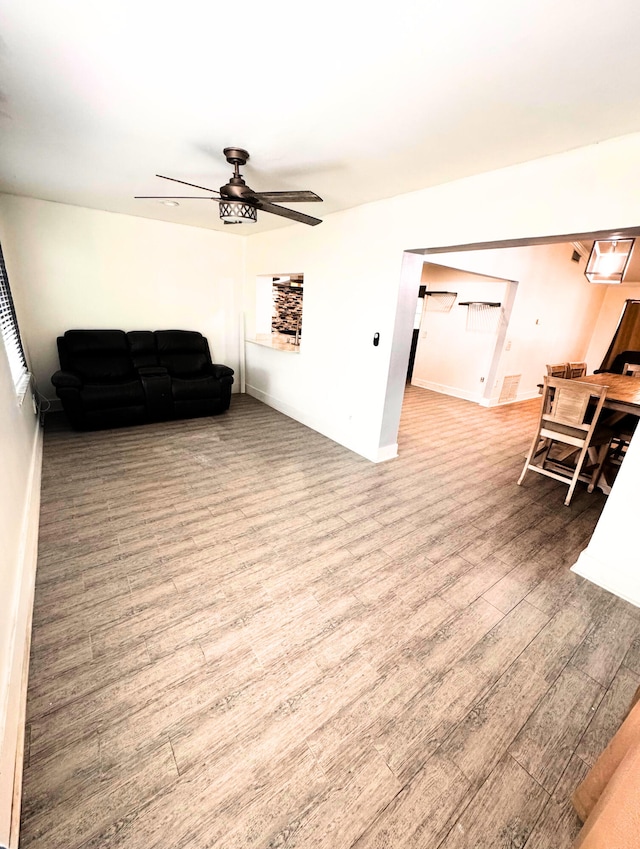 living room featuring ceiling fan, baseboards, and wood finished floors