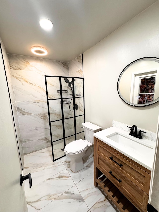 bathroom with toilet, marble finish floor, a tile shower, and vanity