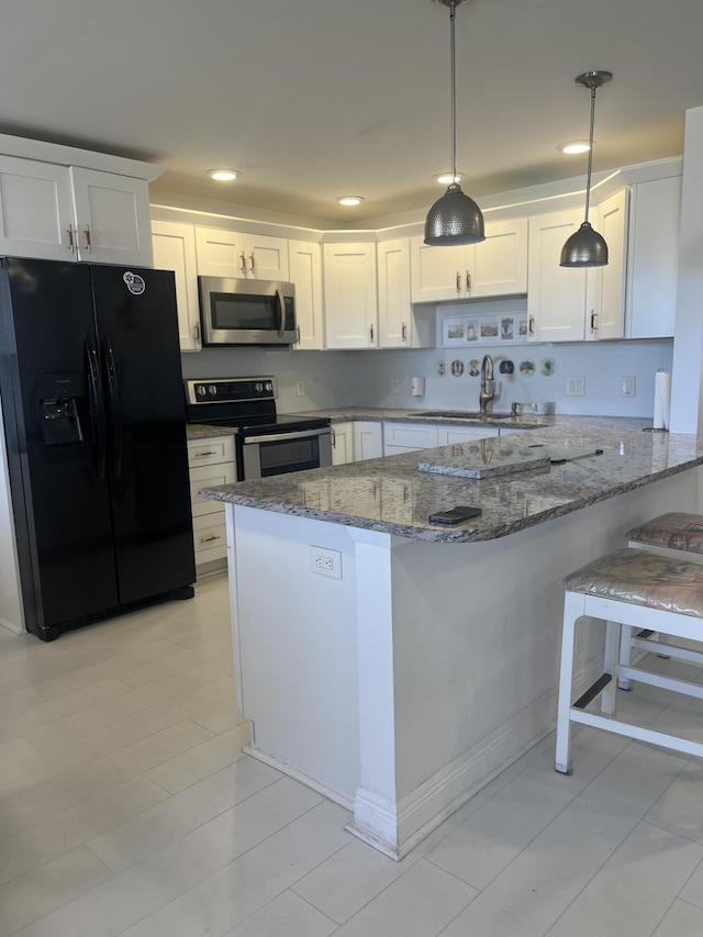 kitchen with stone counters, stainless steel appliances, a peninsula, white cabinetry, and hanging light fixtures