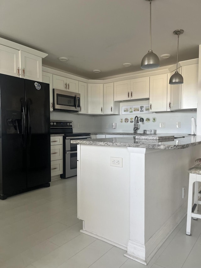 kitchen featuring pendant lighting, stainless steel appliances, white cabinets, and light stone countertops