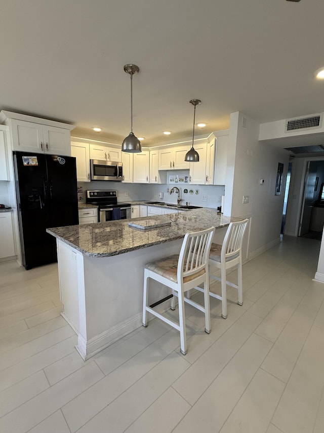 kitchen with visible vents, white cabinetry, dark stone countertops, a peninsula, and stainless steel appliances