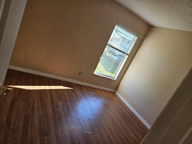 bonus room with baseboards, a textured ceiling, and wood finished floors