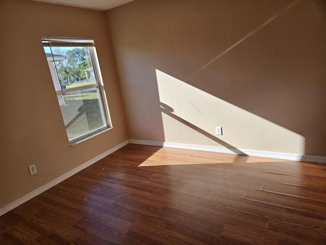 unfurnished room featuring dark wood-style floors and baseboards