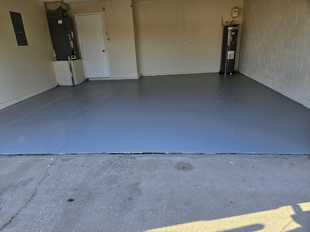 garage featuring electric panel, concrete block wall, and water heater