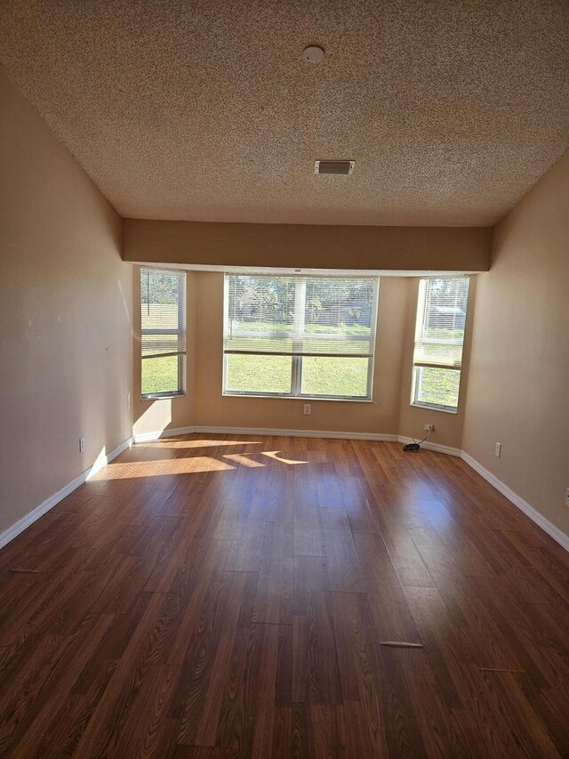 570 Ontario St NW, Palm Bay, FL 32907 - unfurnished room with dark wood-style flooring, a textured ceiling, and baseboards