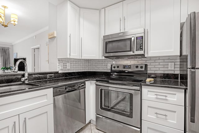 kitchen featuring crown molding, decorative backsplash, appliances with stainless steel finishes, white cabinetry, and a sink