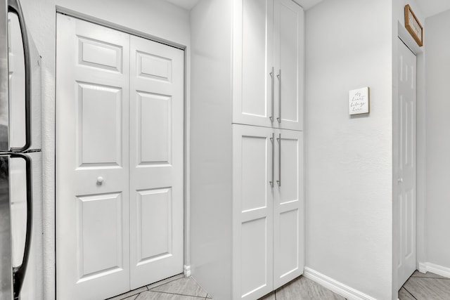 interior space with baseboards and fridge