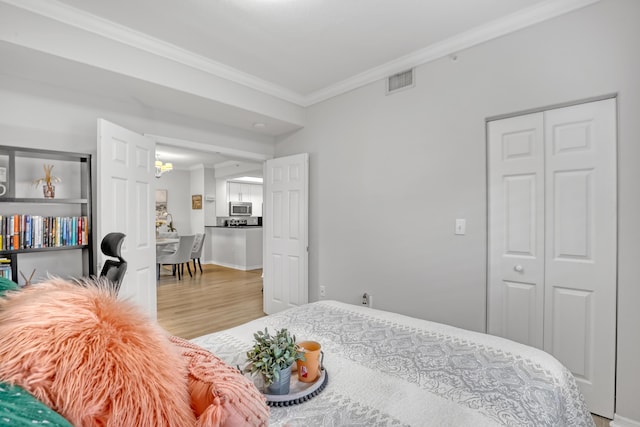 bedroom featuring crown molding, a closet, visible vents, wood finished floors, and baseboards