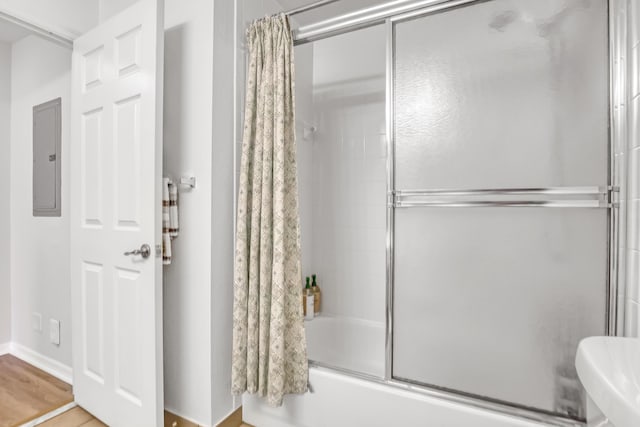 bathroom featuring electric panel, enclosed tub / shower combo, and wood finished floors