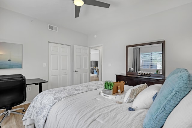 bedroom featuring a ceiling fan, a closet, visible vents, and wood finished floors