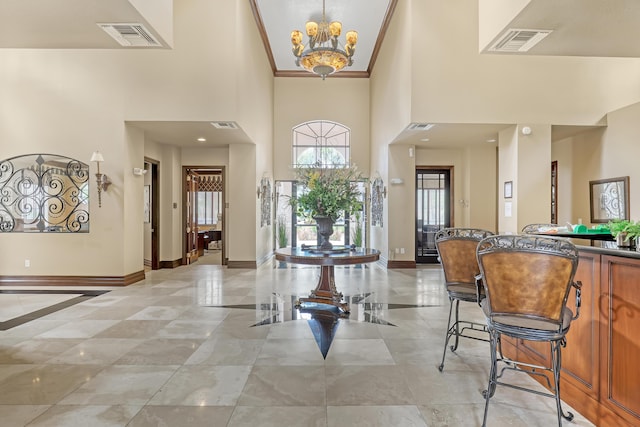 foyer with baseboards, a high ceiling, visible vents, and a notable chandelier