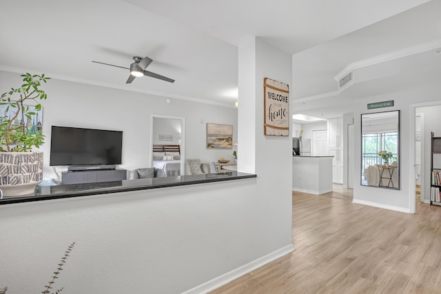 unfurnished living room with ceiling fan, wood finished floors, visible vents, baseboards, and crown molding