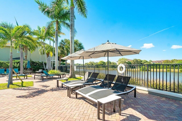 view of patio featuring a water view and fence