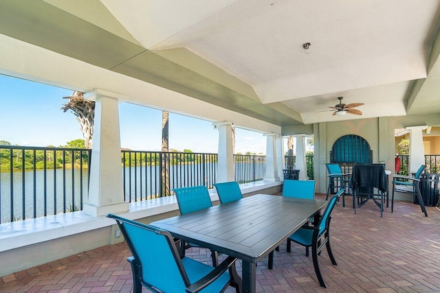 view of patio with outdoor dining area, a water view, and ceiling fan