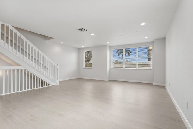 unfurnished living room with baseboards, visible vents, wood finished floors, stairs, and recessed lighting