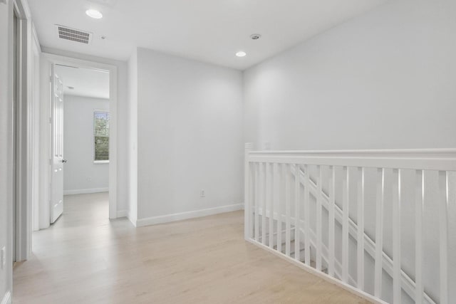 hall featuring light wood-style floors, baseboards, visible vents, and recessed lighting